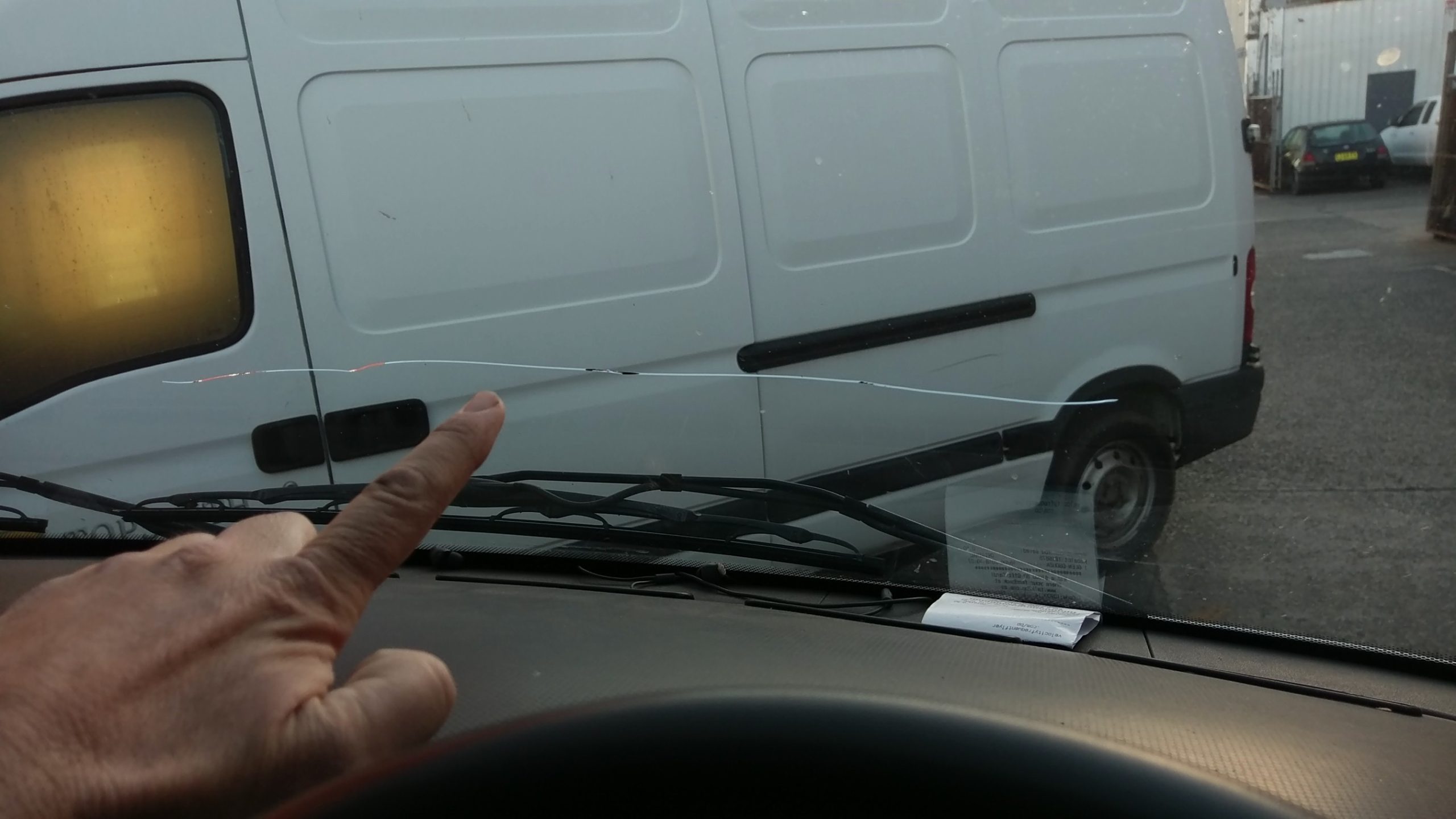 A technician in orange gloves handling a car windscreen with two red suction cups
