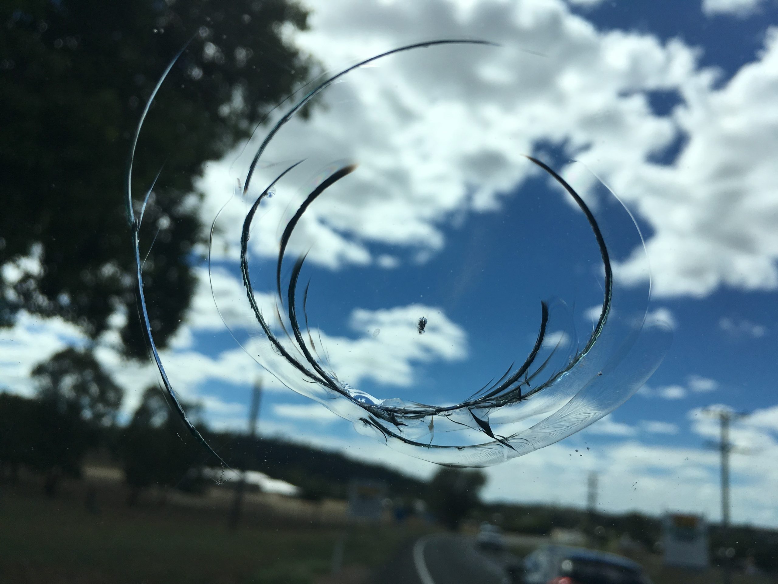 Hands fitting a suction-cup repair bridge over a chip in a car windscreen